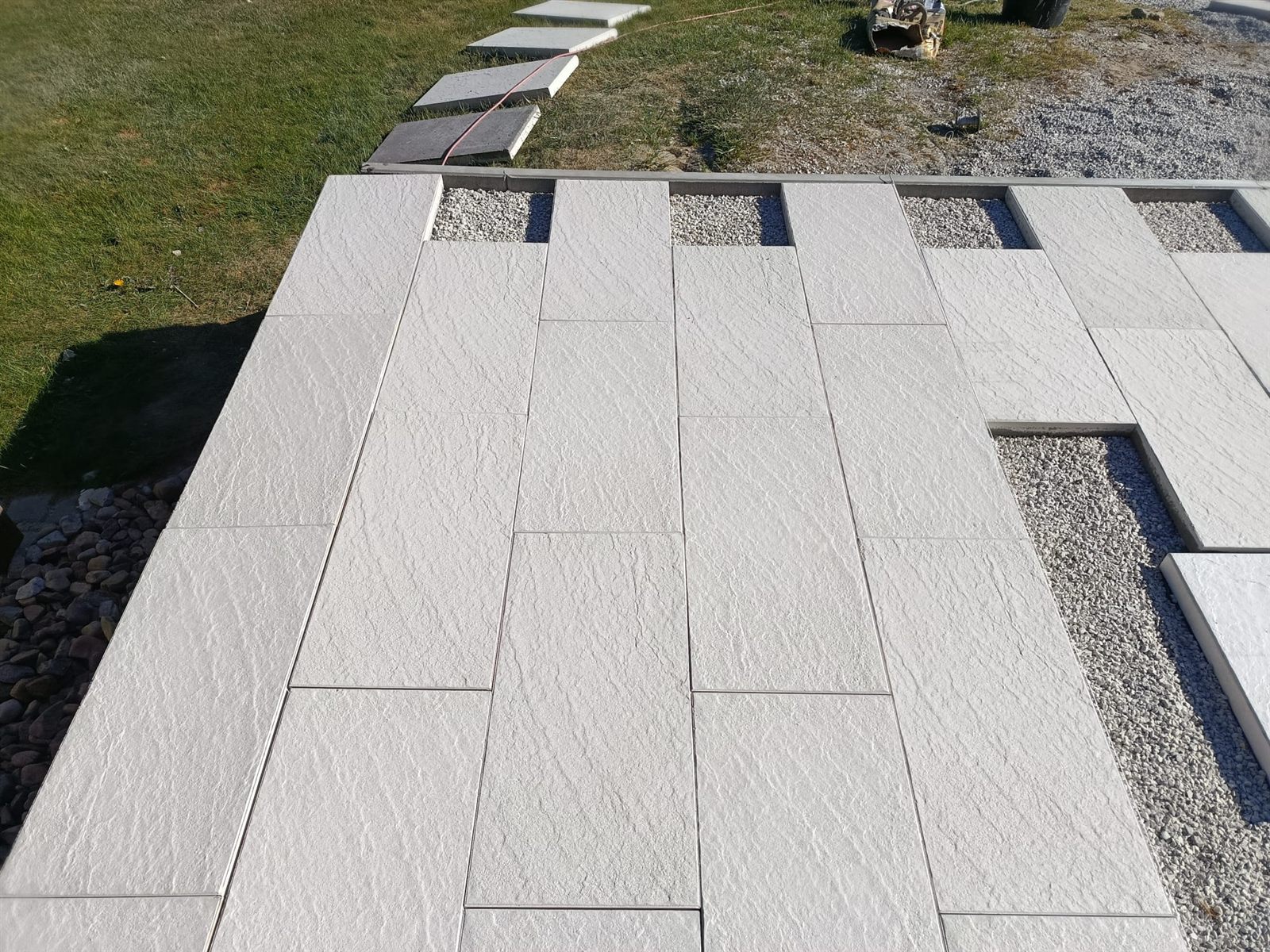 Venkovní velkoformátová dlažba terasy se štěrkovým lemem a trávníkem